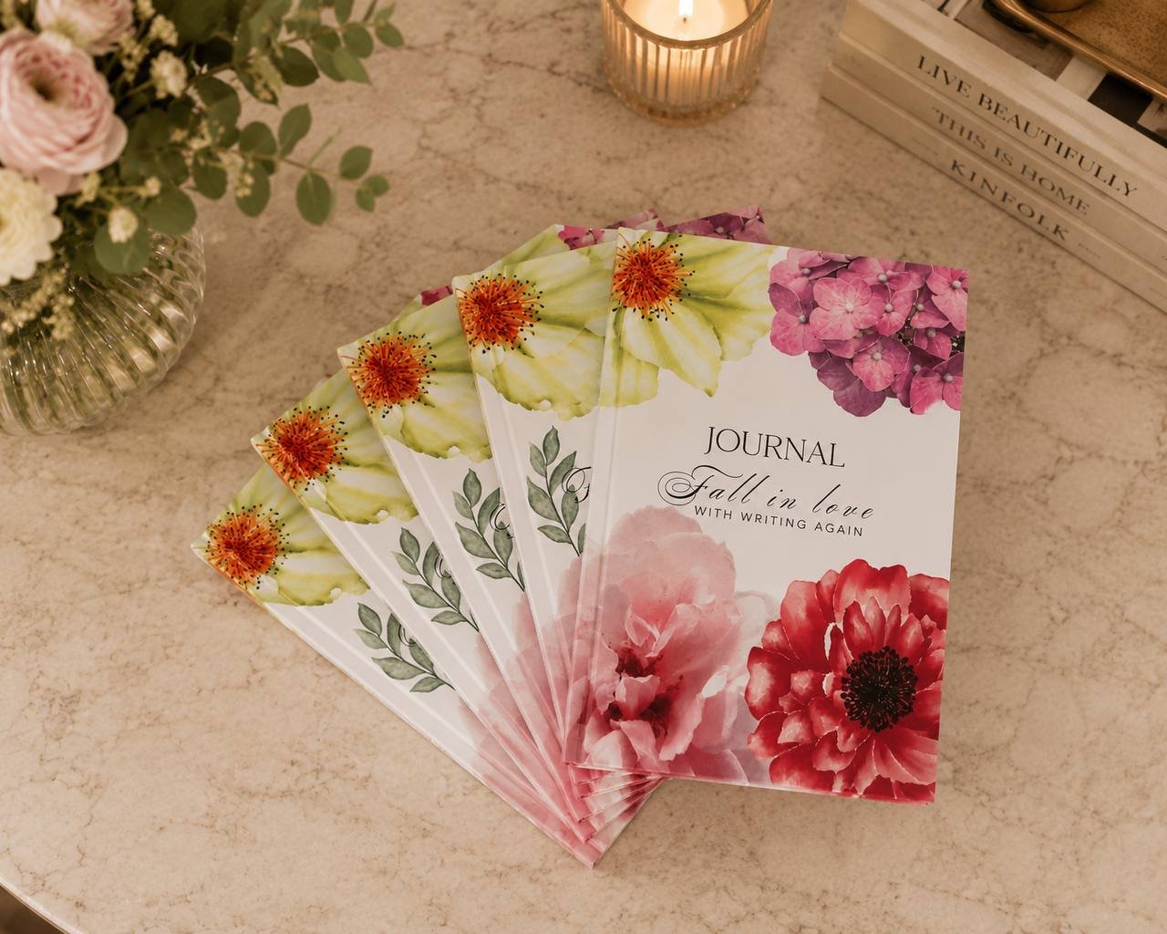 The 90-Day Journal — Fall in love with writing again — fanned out on a marble table with peonies and a candle